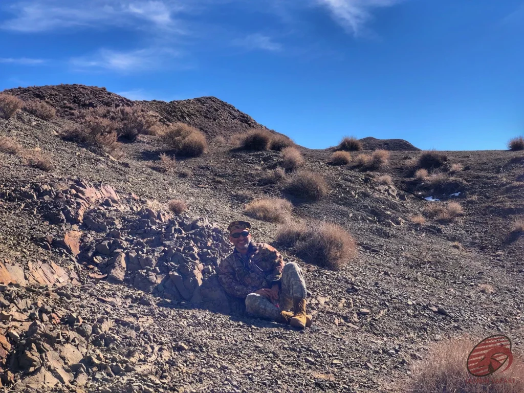 Hunter resting on a rocky scree slope in Iran’s desert highlands, hunt in Iran