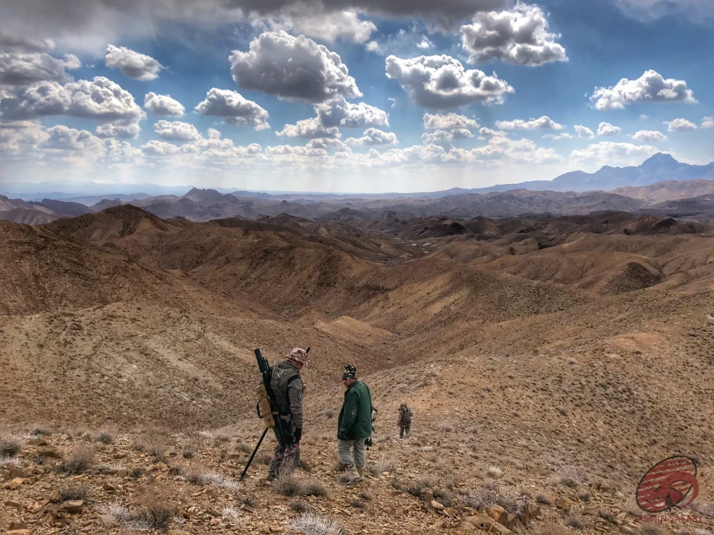 Hunters descending a rocky ridge across a vast highland vista in Iran, hunt in Iran
