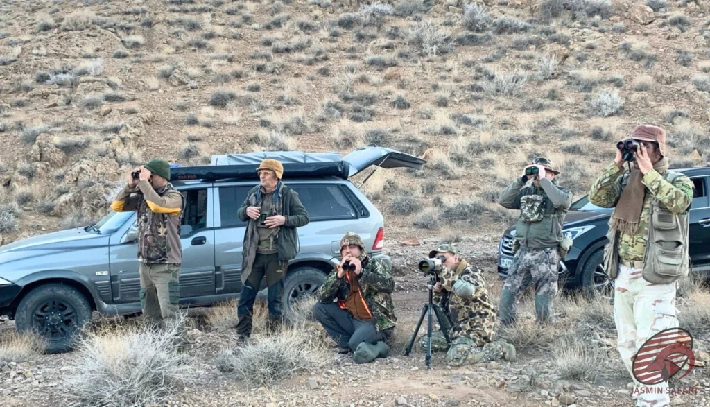 Hunters scouting a rocky valley with binoculars and a spotting scope in Iran, hunt in Iran