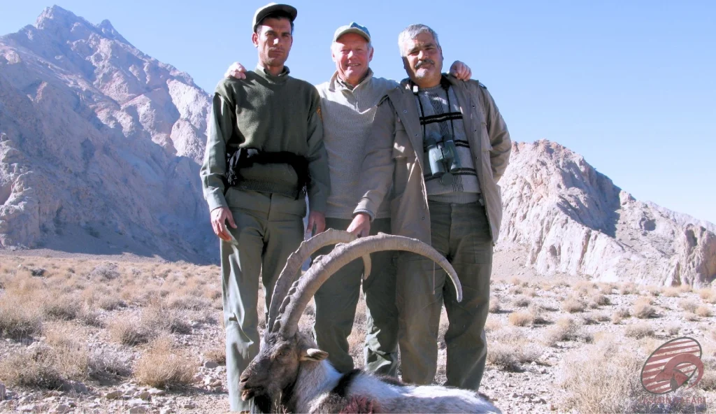 Persian ibex (Capra aegagrus aegagrus) desert-ridge hunting in Iran – group poses with a trophy ibex in arid mountains, hunt in iran adventure.