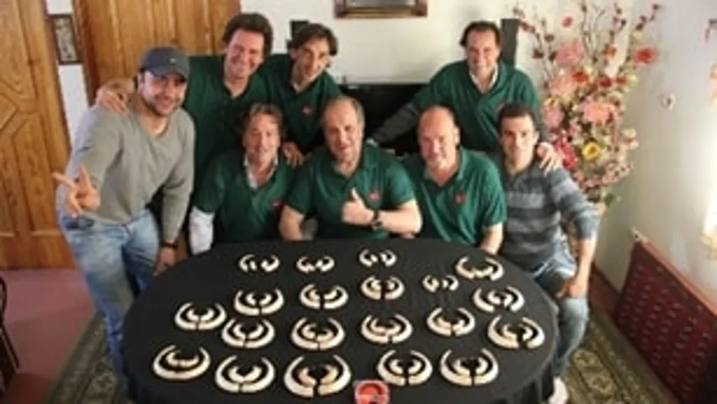 Hunting crew celebrating their successful wild boar haul in a cozy indoor setting, emphasizing teamwork and hunt in Iran.